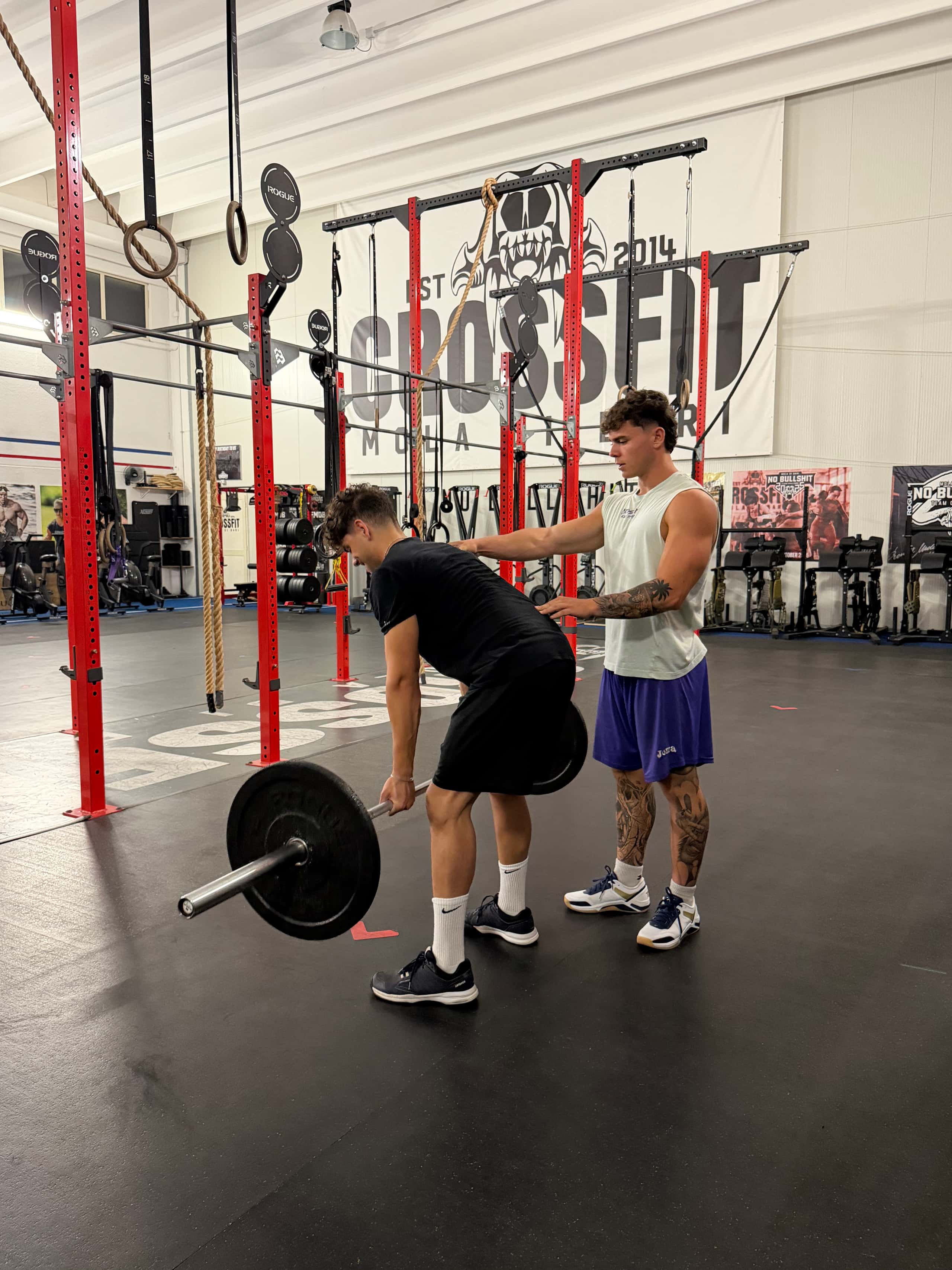 Lorenzo guida la postura di chi si allena davanti allo striscione di CrossFit Mola di Bari